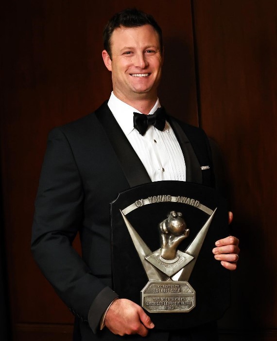 An image of Gerrit Cole posing with his 2023 Cy Young Trophy